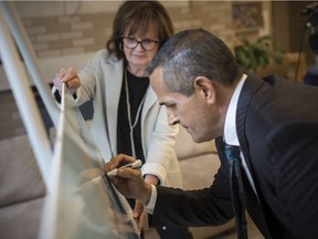 Philanthropist Al Quesnel signs a cheque for$1 million for The Hospice of Windsor and Essex County while executive director Carol Derbyshire looks on Aug. 17, 2018.