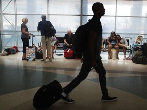 FILE- In this June 29, 2018, file photo, travelers gather on benches to wait for delayed and arriving flights as others make their way to to their gate at the Fort Lauderdale–Hollywood International Airport in Fort Lauderdale, Fla. As summer vacationers start to pack up and head home, Congress is considering a sweeping tally of proposals that could affect travelers, from dictating seat size and legroom to rolling back rules that require airlines to advertise the full price of a ticket.