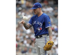 Toronto Blue Jays starting pitcher Sean Reid-Foley uses a dry sack to keep his pitching hand dry on a humid day during the first inning of a baseball game against the New York Yankees, Saturday, Aug. 18, 2018, in New York.