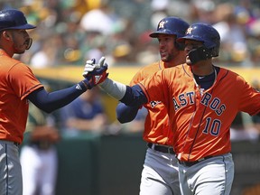 Houston Astros' Yuli Gurriel, right, celebrates with Carlos Correa (1) after hitting a three-run home run off Oakland Athletics' Sean Manaea in the third inning of a baseball game Sunday, Aug. 19, 2018, in Oakland, Calif.