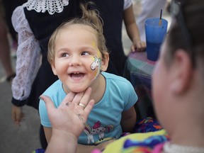 Ariana Karriq, 2, smiles after seeing her painted face done by Skittles the Clown at the St. Angela Merici Festival on Erie Street Aug. 12, 2018.
