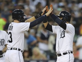Detroit Tigers' Jose Iglesias, right, is greeted at home by Mike Gerber after they both score on Iglesias' two-run home run during the fifth inning of a baseball game against the Minnesota Twins, Friday, Aug. 10, 2018, in Detroit.
