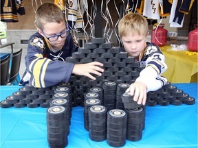 LaSalle Sabres hockey players Cameron Percy, left, and Carson Stowe build a puck mountain during the LaSalle Vipers' tailgate party and Vollmer Culture and Recreation Complex 10th anniversary celebration held Sept. 12, 2018, ahead of the Vipers' season home opener against the London Nationals.