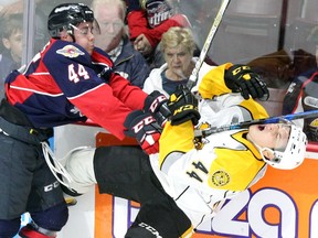 Windsor Spitfires Nathan Staios, left, checks Sarnia Sting Jacob Perreault in the first period of Thursday's OHL exhibition game at the WFCU Centre.