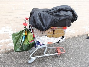 A shopping cart jammed with a suitcase and clothing sits in a public alley beside Windsor's Street Help on Wyandotte Street East, Aug. 20, 2018.