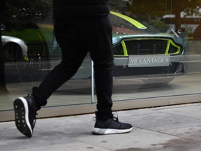 A pedestrian walks past an Aston Martin V8 Vantage in a showroom in central London on August 29, 2018. Aston Martin said today it plans to float one quarter of the British company on the London stock market, as demand rises worldwide for the luxury brand's cars favoured by fictional spy James Bond.