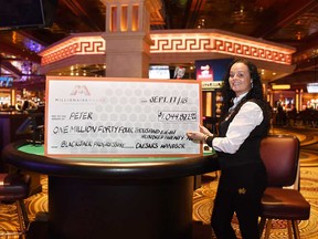 Caesars Windsor dealer Michelle Jubenville stands with a giant cheque to celebrate the $1,044,822 blackjack win by a Leamington player identified as "Peter" on Sept. 17, 2018.