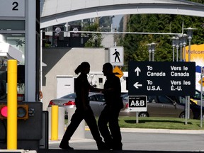 Canadian border guards are silhouetted as they replace each other at an inspection booth at the Douglas border crossing on the Canada-USA border in Surrey, B.C., on August 20, 2009.