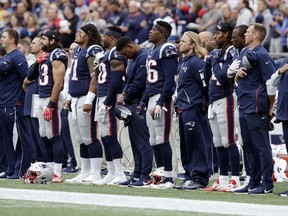 New England Patriots players stand during the national anthem before an NFL football game against the Houston Texans, Sunday, Sept. 9, 2018, in Foxborough, Mass.