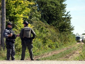 A Windsor police officer and an OPP officer converse while watching over a wooded spot off Concession Road 8 in the Amherstburg area on Sept. 4, 2018. Human remains were discovered in the area the day before.