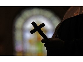 This photo shows a silhouette of a crucifix and a stained glass window inside a Catholic Church.