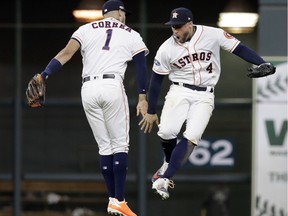 Houston Astros' Carlos Correa (1) and George Springer (4) celebrate their win over Cleveland Indians in Game 2 of a baseball American League Division Series, Oct. 6, 2018, in Houston.