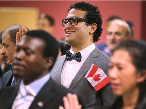 Ryan Ahmed, centre, and other new Canadians are shown during a citizenship ceremony Wednesday at the Immigration, Refugee and Canadian Citizenship office in Windsor.