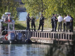 Windsor police investigators gather along the Detroit River near the foot of Mill Street on Thursday after an elderly woman's body was puilled from the water. Police said the body was spotted around 3:30 p.m. near the Festival Plaza at Riverside Drive and Goyeau Street. The woman's identity was unknown, with an autopsy scheduled for Friday.