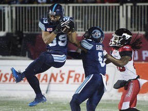 Toronto Argonauts defensive back Matt Black intercepts a pass intended for Calgary Stampeders wide receiver Marken Michel as Argonauts defensive back Jermaine Gabriel looks on during second half CFL football action in the 105th Grey Cup on Nov. 26, 2017 in Ottawa.