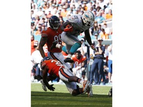 Miami Dolphins running back Frank Gore (21) jumps over Chicago Bears strong safety Adrian Amos (38), during the second half of an NFL football game, Sunday, Oct. 14, 2018, in Miami Gardens, Fla.