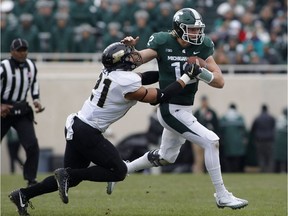 FILE - In this Oct. 27, 2018, file photo, Michigan State quarterback Rocky Lombardi, right, escapes from Purdue's Markus Bailey on a keeper during an NCAA college football game, in East Lansing, Mich. This isn't what Michigan State had in mind at the beginning of the season, but starting Rocky Lombardi at quarterback worked well enough last weekend in a win over Purdue.