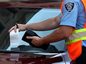 A municipal by-law enforcement officer from Commissionaires issues a parking ticket on Ferry Street in downtown Windsor. Local CUPE officials are urging city council to consider restoring parking enforement as an in-house service.