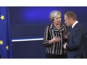 British Prime Minister Theresa May, left, speaks with European Council President Donald Tusk after a group photo during an EU-ASEM summit in Brussels, Friday, Oct. 19, 2018. EU leaders met with their Asian counterparts Friday to discuss trade, among other issues.