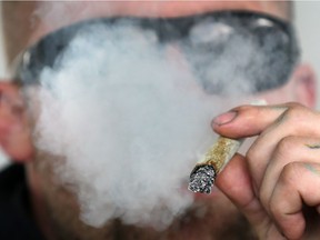 A man smokes marijuana at a legalization party last week in the   400 block of Tecumseh Road West. The province's new rules ban all smoking — including marijuana — outside of city arenas and other recreational properties.