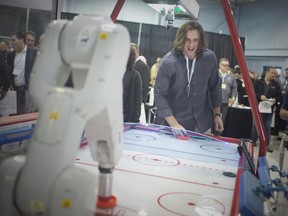 Detroit Lion Luke Willson competes against an ABB Robot in a game of air hockey at the Radix Inc. open house celebrating 24 years, Tuesday, Oct. 16, 2018.