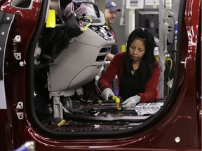FILE - In this Friday, May 6, 2016, file photo, Tina Nguyen works on a 2017 Chrysler Pacifica on an assembly line at the Windsor Assembly Plant, in Windsor, Ontario. On Tuesday, June 21, 2016, Fiat Chrysler Automobiles announced that during the following week, the company plans to stop producing new vehicles in North America with the most dangerous type of Takata air bag inflators. Fiat Chrysler said its factories will stop using inflators that don't have a chemical drying agent. Inflators with a drying agent have been shown in tests to be much safer.
