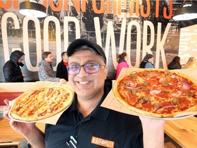 Blaze Pizza general manager Faiz Sheikh proudly displays two signature pizzas at Blaze Pizza on Division Road in Windsor, Nov. 9, 2018. Blaze Pizza celebrated opening the company's newest restaurant by giving away free, build-your-own pizzas.
