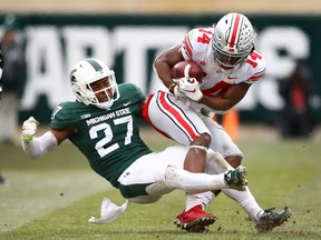 K.J. Hill of the Ohio State Buckeyes battles for yards after a second half catch while being tackled by Khari Willis of the Michigan State Spartans at Spartan Stadium on Nov. 10, 2018 in East Lansing, Michigan.