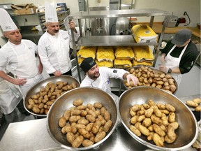 St. Clair College Chef intern Chris Cheswick, centre, and Ber Viravouth, right, prepare seasoned potatoes for the annual Potato Fest fundraiser for In Honour of The Ones We Love November 27, 2018. Chefs Carmine Incitti and Mark MacDonald, left, stopped by to check on progress.