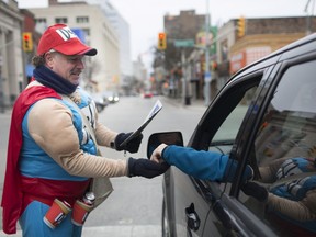 Jamie Tesolin, from Windsor Fire and Rescue, hands out Goodfellows newspapers at the intersection of University and Ouellette avenues on Thursday, Nov. 22, 2018.