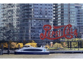In this Nov. 7, 2018, photo, a water taxi approaches the Long Island City waterfront and new high-rise luxury apartment buildings, passing the landmarked PepsiCola sign in Gantry Plaza State Park in the Queens borough of New York. On Tuesday, Nov. 13, Amazon said it will split its second headquarters between Long Island City in New York and Crystal City in northern Virginia.