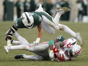 Michigan State linebacker Joe Bachie flips over Michigan State cornerback Josiah Scott as Scott tackles Ohio State wide receiver Terry McLaurin during the second half of an NCAA college football game on Nov. 10, 2018, in East Lansing, Mich.
