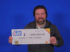 Orlando Jr Nalli, 45, of Windsor, holds up his million-dollar prize cheque at the Ontario Lottery and Gaming Corporation's Prize Centre in Toronto on Nov. 27, 2018.
