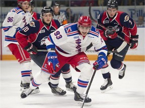 Kitchener Rangers player Jonathan Yantsis, centre, chases after a loose puck in the slot in front of the Windsor net, as Spitfires Jordan Frasca, left, and #3 Grayson Ladd, right, go after him.