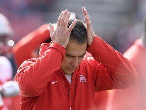 In this  Saturday, Nov. 17, 2018 photo, Ohio State head coach Urban Meyer holds his hands to his head before an NCAA football game against Maryland in College Park, Md. Urban Meyer doesn't seem to be having much fun these days. The Ohio State coach is not demonstrably mirthful, of course, at least not when it comes to his job. But the 54-year-old Meyer's sideline demeanor has taken on a decidedly beleaguered stoop this season. The usual shouting and gesticulating, the ripping off his headset, those are often followed by a hand moving up to the left side of his head because of severe headaches.