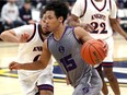 Assumption Purple Raiders point guard Kassen Byas carries the ball against Andre Familia, left, of Holy Names during the consolation final of the 62nd Annual Invitational High School Basketball Tournament at St. Denis Centre Saturday.