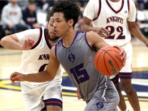 Assumption Purple Raiders point guard Kassen Byas carries the ball against Andre Familia, left, of Holy Names during the consolation final of the 62nd Annual Invitational High School Basketball Tournament at St. Denis Centre Saturday.