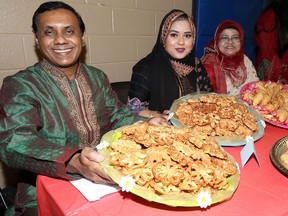 Bangladesh Canadian Association president Saiful Bhuiyan, left, his daughter Shapnil Bhuiyan and Syeda Sultana, right, display sweet 'pitha' during the National Victory Day of Bangladesh celebrations at Optimist Community Centre.
