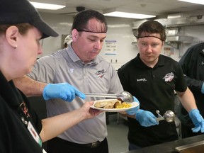 Windsor Spitfires staffers Bill Bowler, left, Evan Mathias and Steve Horne work in the kitchen of Downtown Mission at the annual Christmas Dinner.  About 350 prime rib dinners and trimmings were served to area needy. Spitfires mascot Bomber and Santa Claus arrived following the sit down portion of the dinner.