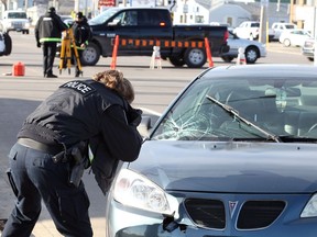 A Windsor police collision investigator photographs the damaged windshield of a car that struck a 68-year-old woman near the intersection of Banwell Road and Tecumseh Road East on the morning of Dec. 18, 2018.