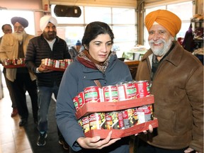 Helping hands. Windsor Sports and Culture Centre member Harjeet Singh carries two flats of large cans of soup as club president Jatinder Rai, right, smiles and other members participate Dec. 27, 2018, in the WSCC annual donation of money, goods and clothes to Windsor's Street Help Homeless Centre.