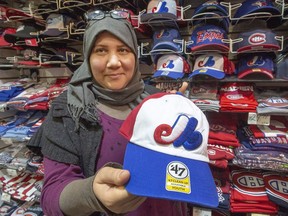 Karina Benami holds up a Montreal Expos baseball cap at the Jannat Souvenir shop on Dec. 13, 2018, in Montreal. Fourteen years after their last game here there is still interest in acquiring another major league baseball franchise.
