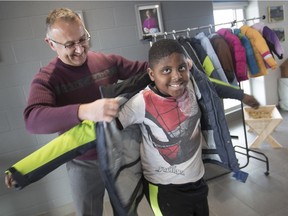 Enoch Dugbor, 7, a Grade 2 student at St. Teresa of Calcutta Catholic School, gets help trying on a winter coat from Terry Lyons, director of eduction at the Windsor-Essex Catholic District School Board, that was provided by the Knights of Columbus, on Monday, December 17, 2018.
