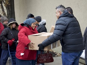 Windsor resident Mana Mahamed receives a boxful of holiday foods, including a frozen turkey, from Vince Gervasi, a member of the Canadian Italian Business and Professional Association, on Dec. 22, 2018, at the Goodfellows building in Windsor.