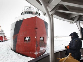 Canadian Coast Guard Griffon crew member Dave Smith from Kingsville checks status of the Arthur M. Anderson freighter stuck in the ice in the St. Clair River near Windsor on Feb. 26, 2015. The Samuel Risley, (L) also helped breaking a path for the freighter.