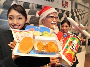An employee of Japan Airlines shows off a plate of "AIR Kentucky Fried Chicken" at a press conference to announce their new in flight food service in Tokyo on November 28, 2012.