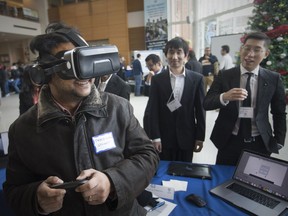 Electrical engineering student Tareq Supon takes a virtual reality campus tour — produced by computer science graduate students, Shawn Ohn, right, and Jinchao Wu, centre — during the 3rd annual Computer Science Demo Day in the CAW Student Centre on Nov. 30, 2018.
