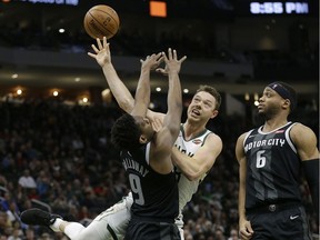 Milwaukee Bucks' Matthew Dellavedova, middle, is, fouled between Detroit Pistons' Langston Galloway (9) and Bruce Brown (6) during the second half of an NBA basketball game Wednesday, Dec. 5, 2018, in Milwaukee.