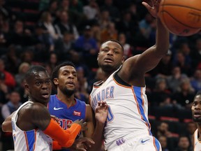 Detroit Pistons guard Ish Smith, center, passes the ball while defended by Oklahoma City Thunder guard Dennis Schroder, left, and guard Deonte Burton, right, during the first half of an NBA basketball game, Monday, Dec. 3, 2018, in Detroit.