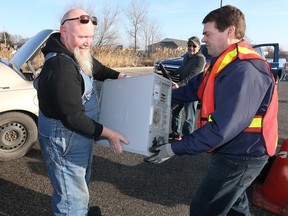 James Devine left, unloads three computers and two TVs at the Habitat for Humanity Essex-Windsor Electronics Waste Recycling event at Home Depot Saturday morning. Assisting was Habitat volunteer Mark Rawlings, right.